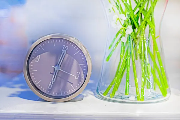 stock image alarm clock on a bedside table with flowers. Good morning. Changing the clock. Daily routine