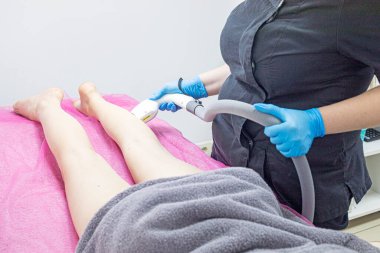 Kozmetik uzmanı bacağındaki fazla kılları lazer cihazıyla alıyor. Vücut bakımı ve güzellik