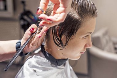 Berber bir gencin saçlarını güzellik salonunda kesiyor. Kişisel stil