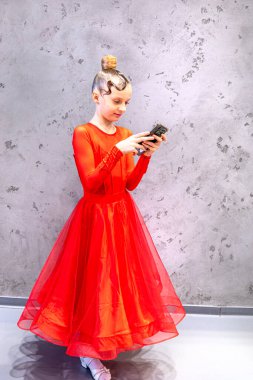 girl with a beautiful hairstyle in a ballroom sports dress takes a selfie on the phone after the tournament. clipart