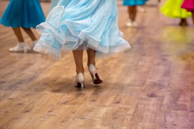 Güzel mavi elbiseli kızlar ve diğer renkli elbiseler bir balo dansı turnuvasından önce antrenman yapıyorlar.