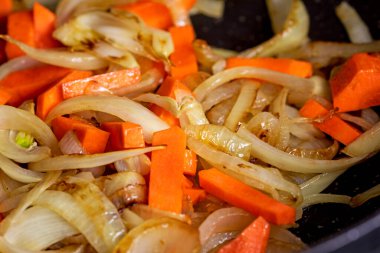 Tencerede taze havuç parçalarıyla yarım soğan halkası kızartıyorum. Vejetaryen beslenme ve sağlık