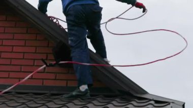 İşçi bulutlu havada çatıya güneş panelleri kurar. Güneşten gelen enerji