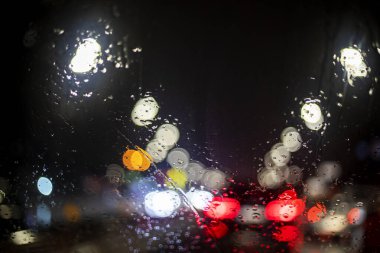 reflections of red brake lights from a car windshield in the rain in a traffic jam. Road safety. Poor visibility clipart