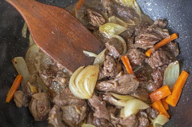 Kızartma tavasında soğanlı yahni ve havuç pişirmek.