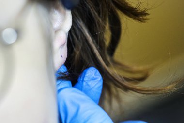 Mavi eldivenli güzellik uzmanı kulakların delineceği yeri işaretliyor. Tarz ve güzellik