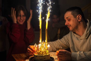 Babam 15. yaş gününde kızları için fıstıklı kekin üzerinde altın numaralarla mum yakar. Doğum günü. Yıldönümünü kutla