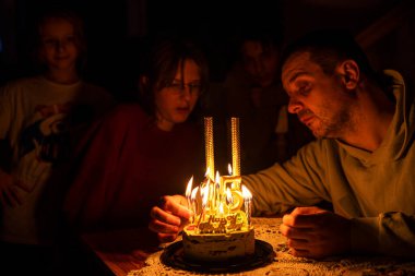 Babam 15. yaş günü için mumları yakıyor. Ailesi tarafından çevrelenmiş olan kızına, fıstıklı kekin üzerinde altın numaralar var. Doğum günü. Yıldönümünü kutla