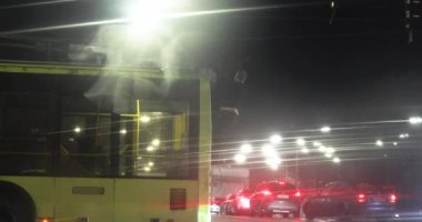 Karanlıkta bir trafik sıkışıklığında U şeklindeki bir kavşakta yağmurda tramvaydan kornalar çalınır.