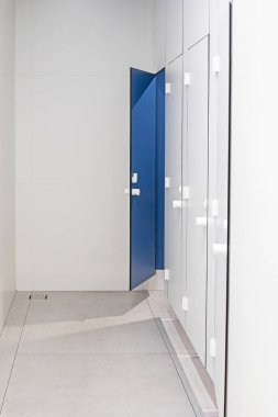 Bir süpermarkette, aydınlık bir iç mekanda tuvaletin mavi kapıları.