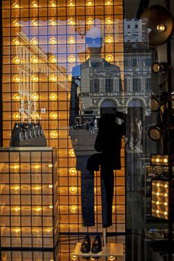 Akşamları vitrinden bir manken ve bir binanın yansıması. Moda ve tarz Avrupa 'da seyahat