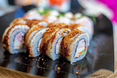 Suşi ruloları, açık bir pakette filizlenmiş bezelye filizli yılan balığı ve karides parçaları.