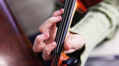 Sol eliyle kemanla hızlı bir melodi çalmaya çalışan kız. El ve parmak pozisyonu.
