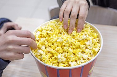 Erkek ve kız kardeş sinemada film izlemeden önce peynirli patlamış mısır yerler. Aile gezisi.