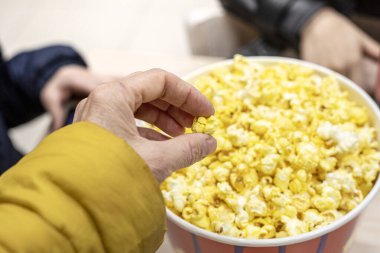 Erkek, kız kardeş ve anne sinemada film izlemeden önce peynirli patlamış mısır yiyorlar. Aile gezisi.