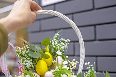 Elinde yumurta ve dekoratif çiçeklerle bir Paskalya sepeti vardı. Paskalya tatili