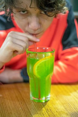 Parlak kazaklı çocuk doğal yeşil limonata içiyor.