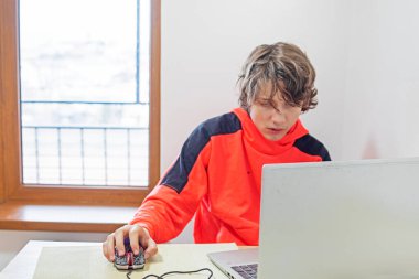 Genç çocuk mutfaktaki bilgisayarın başında çalışıyor.