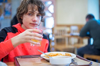 Ergen çocuk bir mola sırasında okul kantininde öğle yemeği yiyor. Okul sağlığını izle