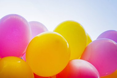Mavi gökyüzünün arka planına karşı çok renkli şişme balonlar. Tatil