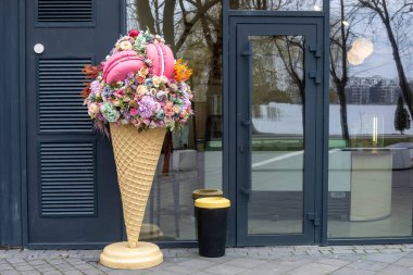 Modern bir kafenin girişinde çiçekli ve kurabiyeli bir dondurma.