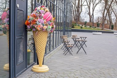 Modern bir kafenin girişinde çiçekli ve kurabiyeli bir dondurma.