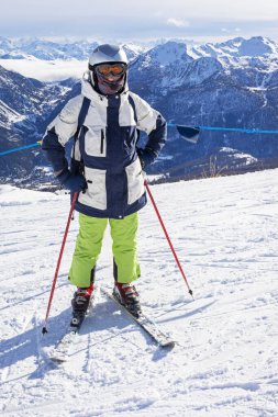Alplerdeki İtalyan kayak merkezine inmeden önce yamaçta genç bir kayakçı. Tatil