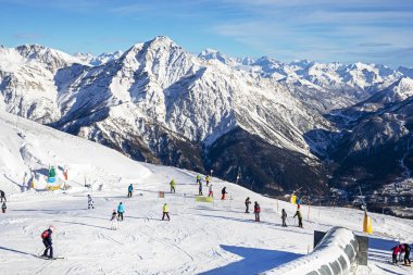 Güneşli bir günde Alplerdeki bir İtalyan otelinde bir dağın tepesinde kayakçılar. Sezonun açılışı
