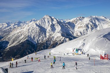 Güneşli bir günde Alplerdeki bir İtalyan otelinde bir dağın tepesinde kayakçılar. Sezonun açılışı