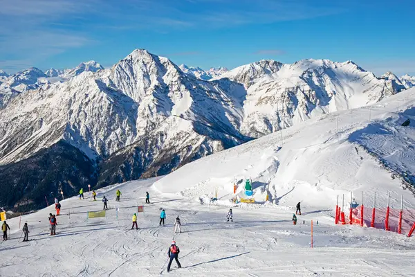 Güneşli bir günde Alplerdeki bir İtalyan otelinde bir dağın tepesinde kayakçılar. Sezonun açılışı