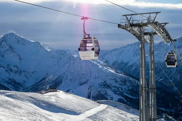 Alplerdeki bir dağın tepesindeki kayak asansörü güneşin erken ışıklarıyla aydınlanır.