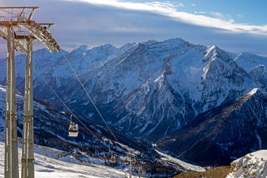 Alplerdeki bir dağın tepesinde sabah güneşinde kayak asansörü.