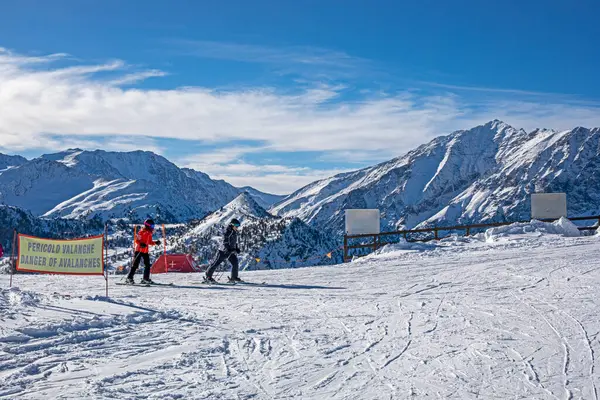 Güneşli bir günde Alplerdeki bir İtalyan otelinde bir dağın tepesinde kayakçılar. Sezonun açılışı