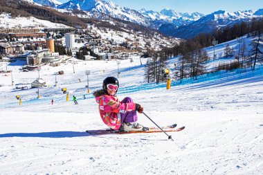 Mutlu küçük kayakçı Alplerdeki yamaçta oturur. En İyi Okul Tatilleri