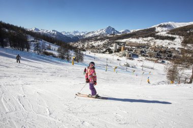 Alplerdeki bayırda küçük mutlu bir kayakçı. Okul tatili