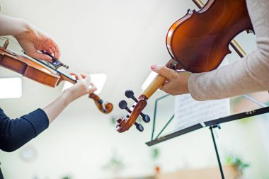 Genç kemancı kız bir öğretmenle müzik dersinde notalardan bir şeyler öğreniyor. Müzikal gelişme