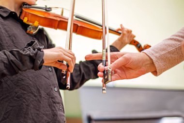 Siyahlı kız kemancı kız bir öğretmenle müzik dersinde notalardan bir şeyler öğreniyor. Müzikal gelişme