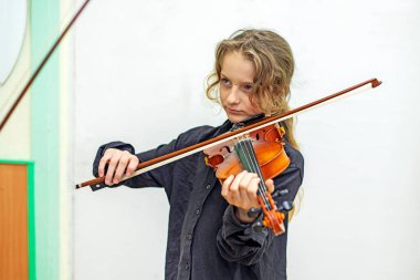 Siyahlı kız kemancı kız bir öğretmenle müzik dersinde notalardan bir şeyler öğreniyor. Müzikal gelişme
