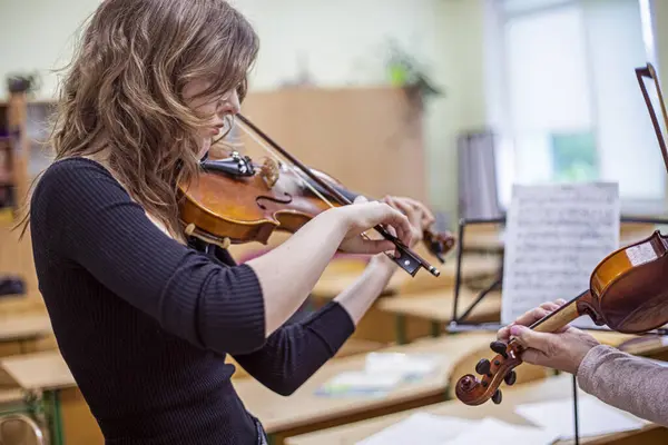 Genç kemancı kız bir öğretmenle müzik dersinde notalardan bir şeyler öğreniyor. Müzikal gelişme
