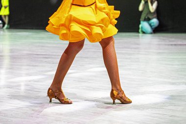  Turnuvadan önce parlak turuncu Latin Amerika elbisesi giyen genç kız. Salon dansı.