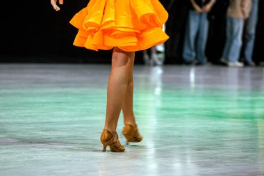 Turnuvadan önce parlak turuncu Latin Amerika elbisesi giyen genç kız. Salon dansı.