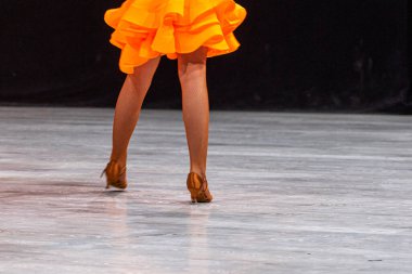 Turnuvadan önce parlak turuncu Latin Amerika elbisesi giyen genç kız. Salon dansı.