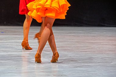 Turnuvadan önce parlak turuncu Latin Amerika elbisesi giyen genç kız. Salon dansı.