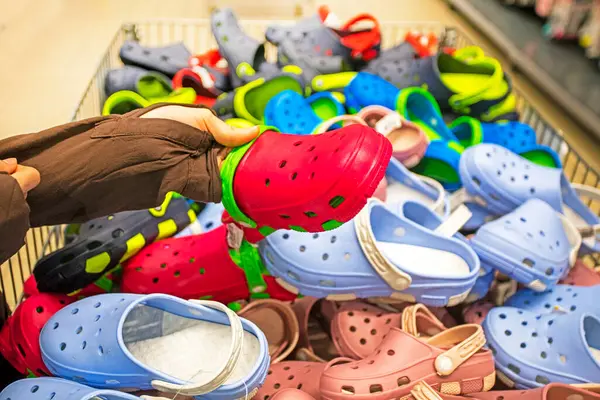 Süpermarketteki bir konteynırda yazlık lastik timsahları seçmek.