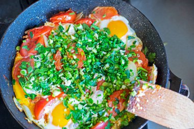 Çırpılmış yumurta, domates ve tavada yeşil soğan pişirmek.