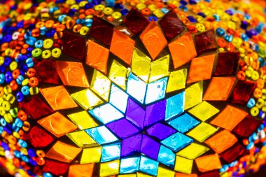 Karanlık arka planda, geometrik desenli, boyalı cam lamba.