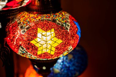 Kırmızı gölgeli geometrik desenli koyu bir zemin üzerinde boyalı cam lamba.