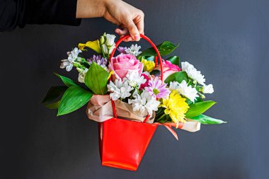 Gri arka planda çiçeklerle dolu bir çiçek sepeti tutuyordu. Kutlarım. Kadınlar Günü, Anneler Günü