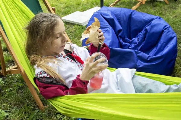  Kız hamakta limonata içiyor ve dışarıdaki yüksek lisans sınıfları arasında sandviç yiyor.
