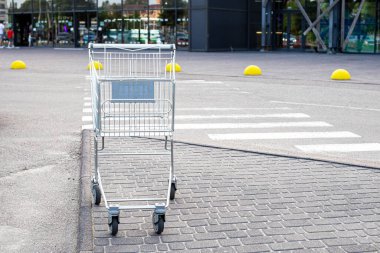 Süpermarketin yanındaki otoparkta metal market arabası var.
